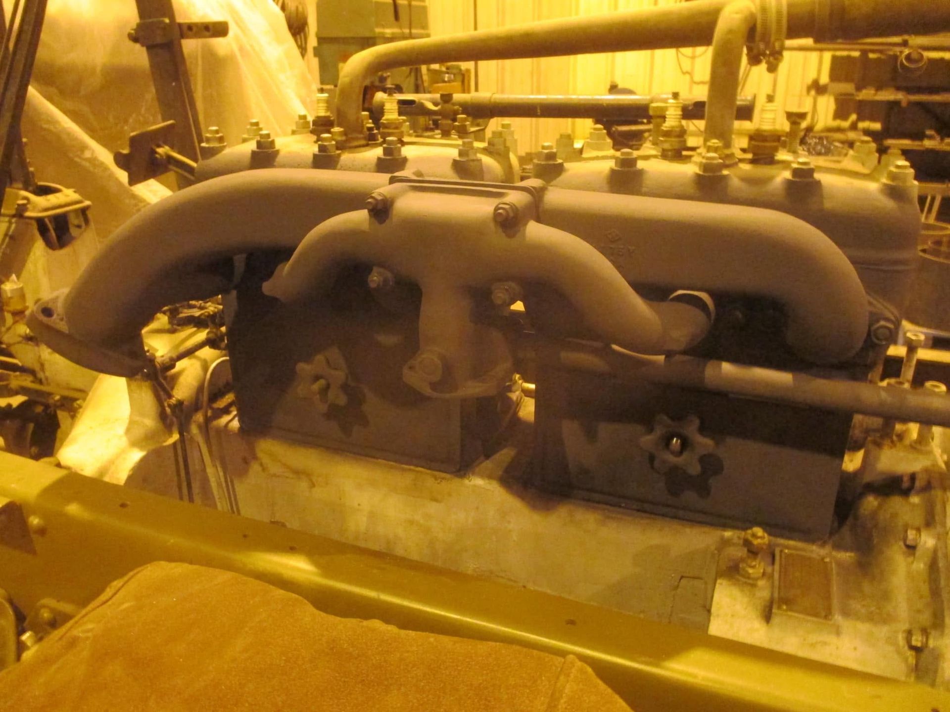 Yellow-tinted industrial machinery with large pipes and valves in a factory setting