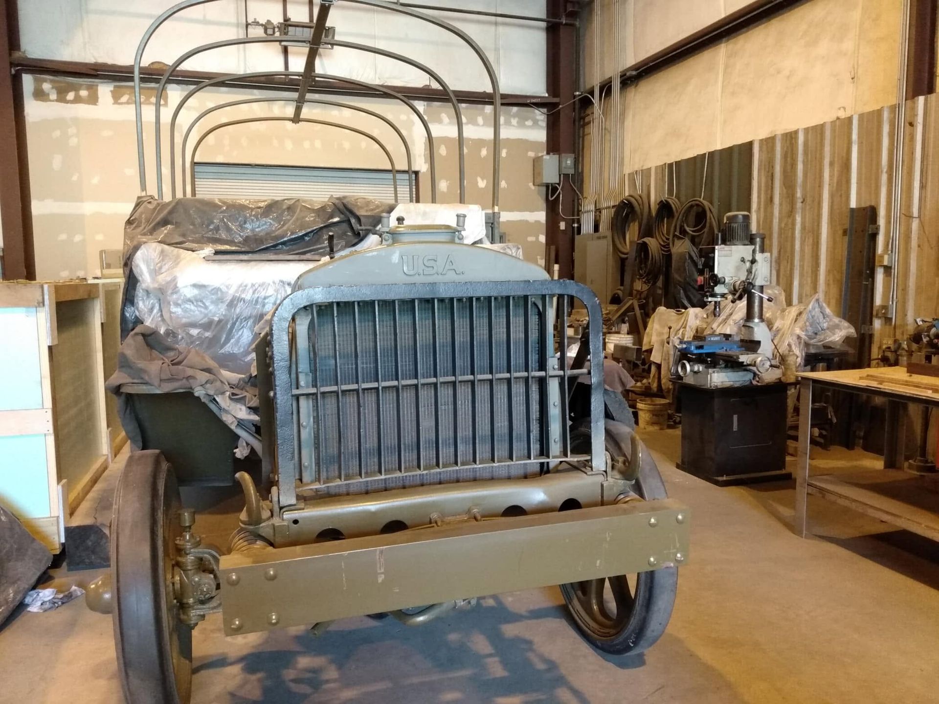 Old vintage truck in a workshop, front view with blue grille and tan body panels