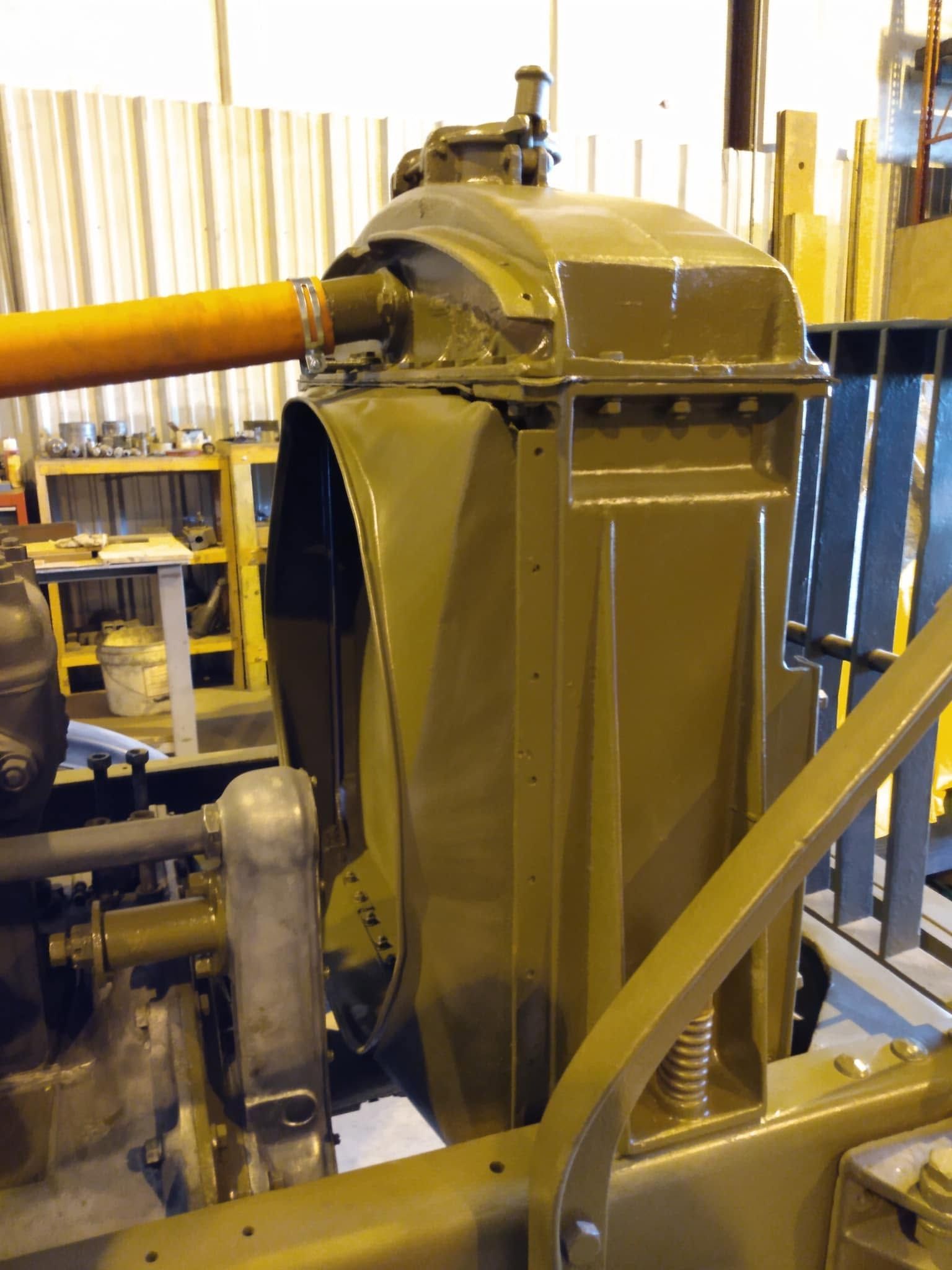 Yellow industrial machine in a workshop, with pipes and metal framing nearby.