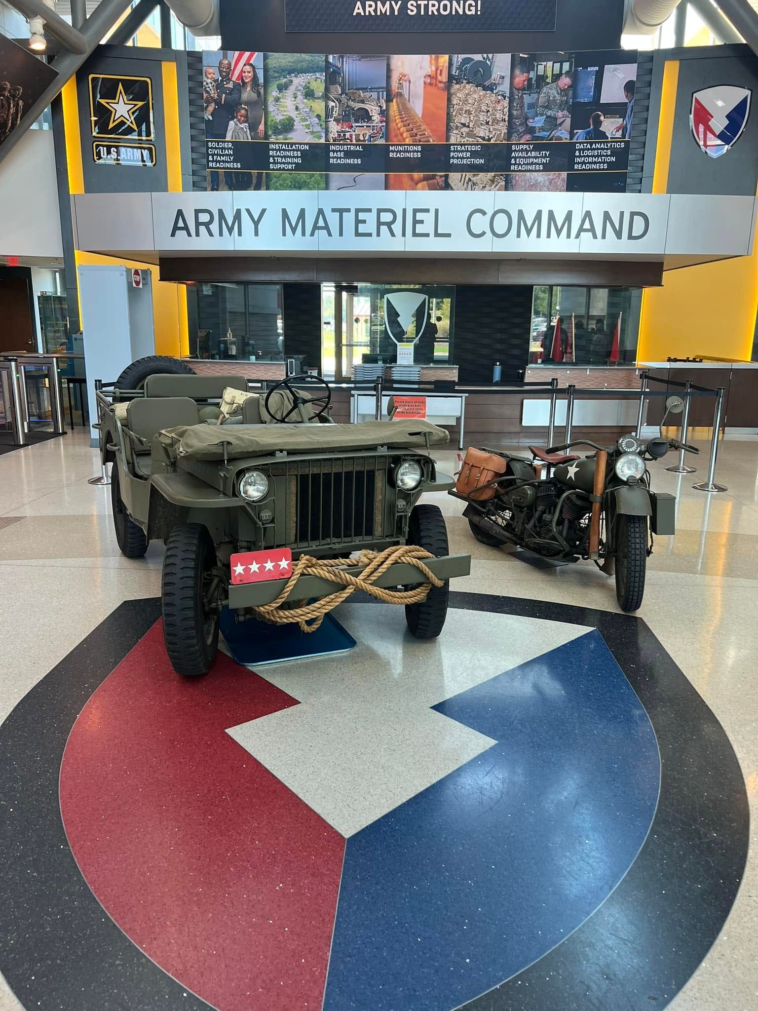 Army materiel command display with a military jeep on a red, white, and blue floor emblem indoors