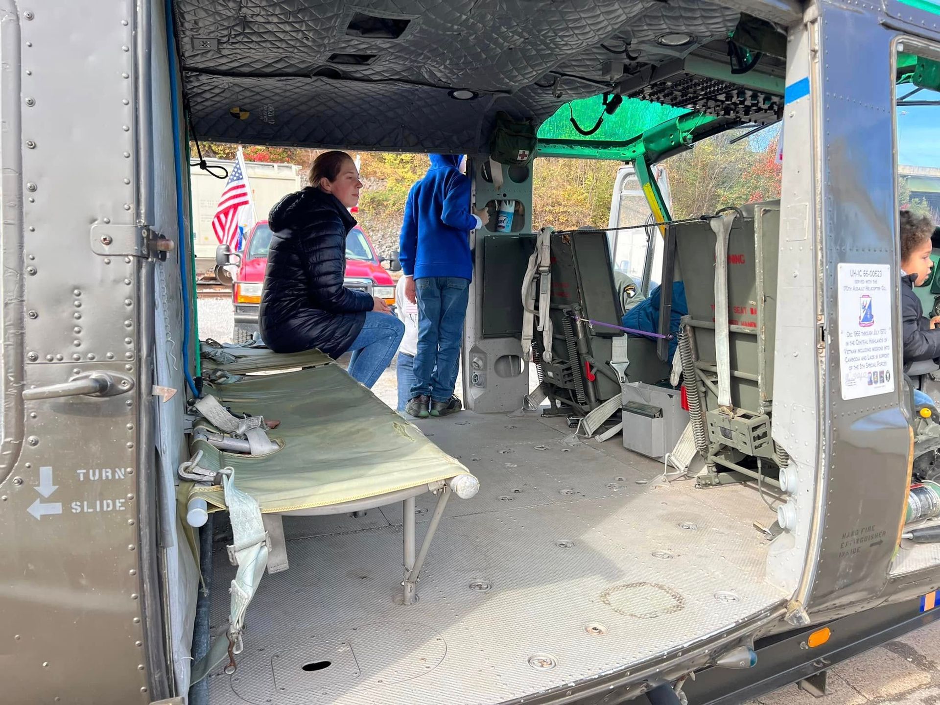 Inside a damaged vehicle interior, two people inspect debris and torn seats.
