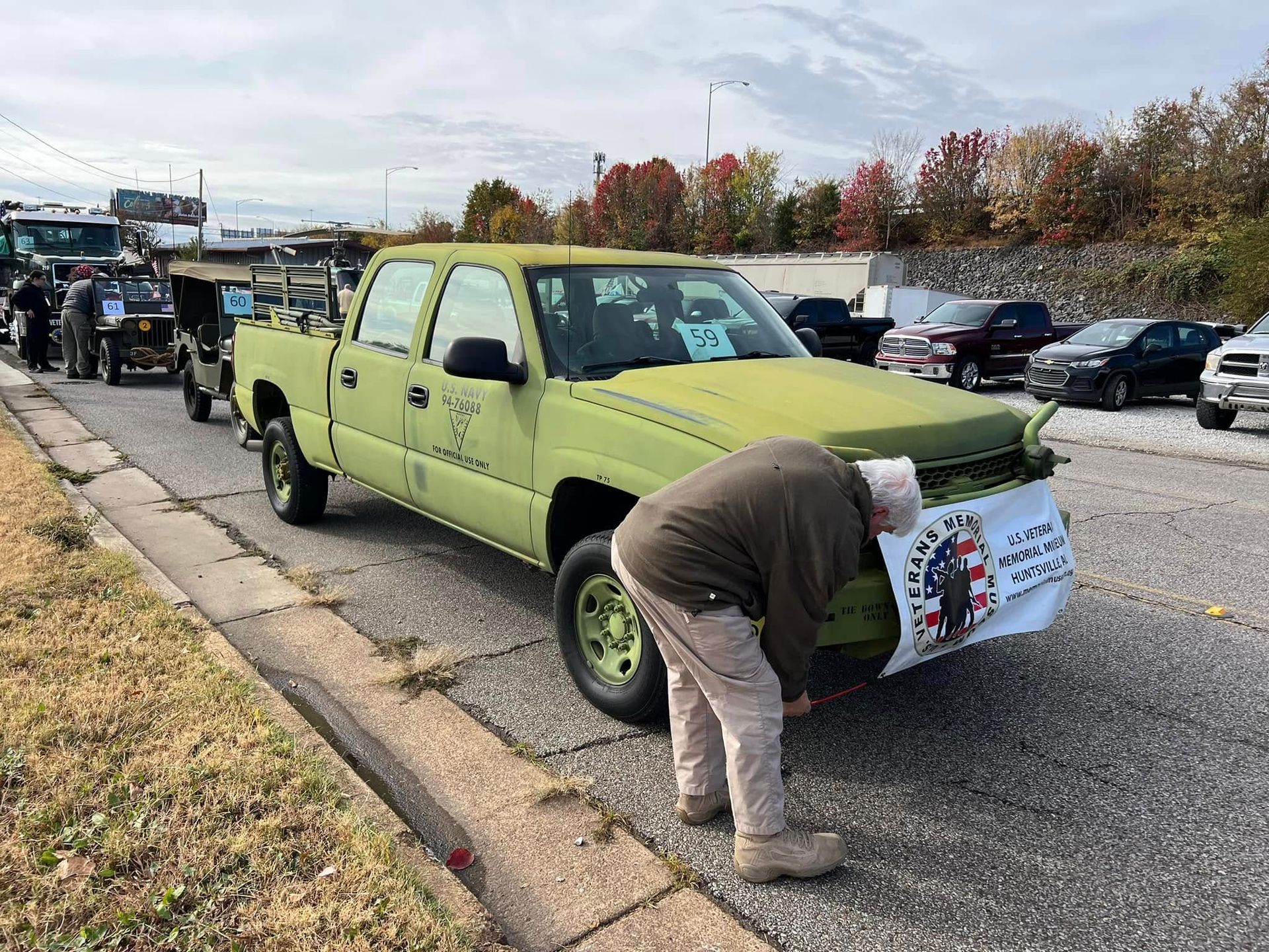 Lime-green pickup truck in a parking lot with a person placing a sign on the front bumper.