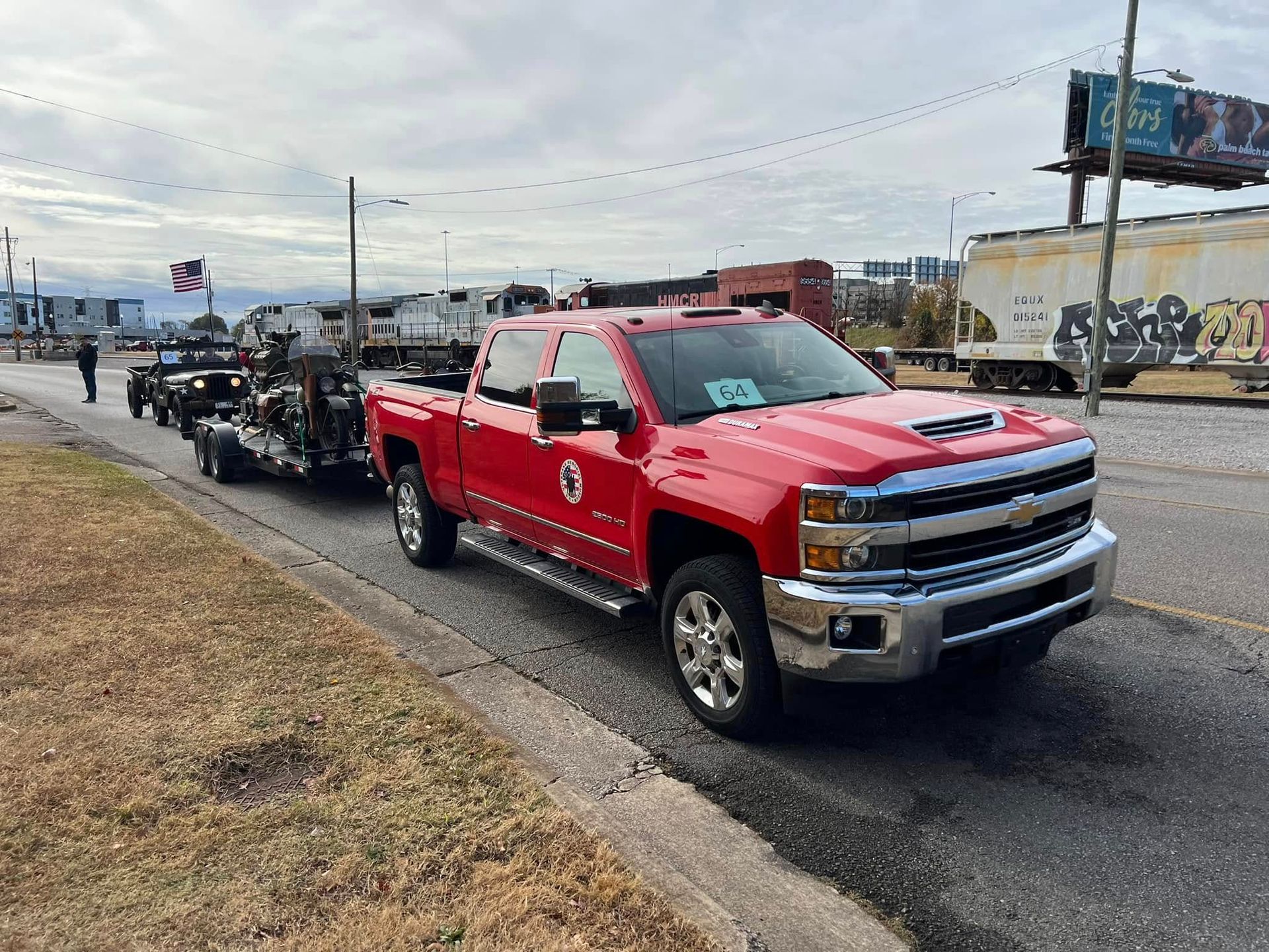 Red pickup truck leading a motorcycle procession on a wet road near an intersection