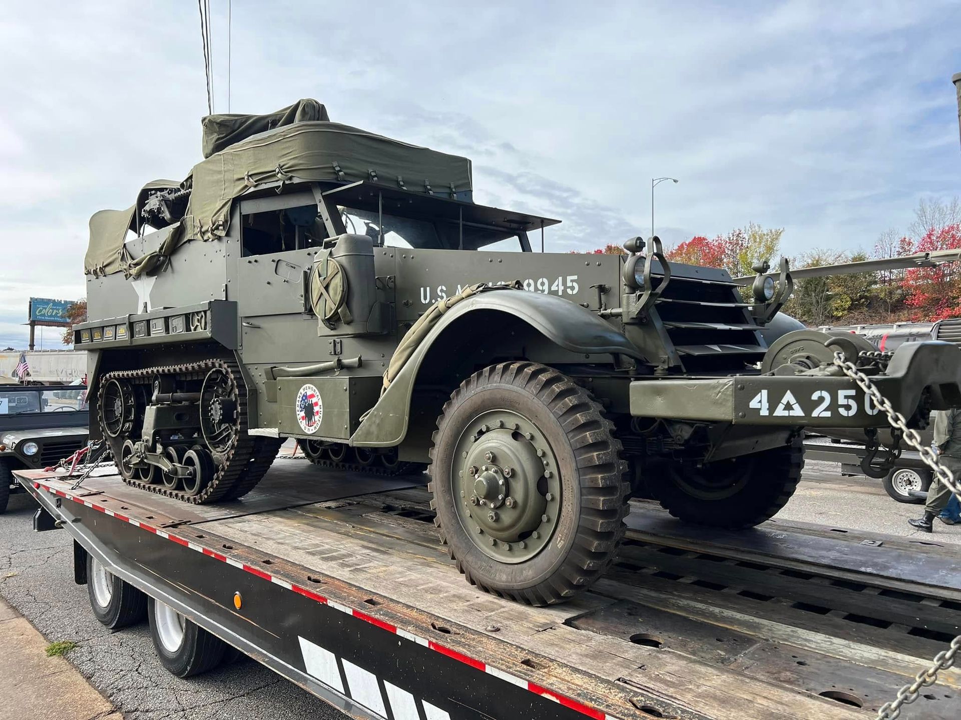 Olive-drab military half-track on a trailer at an outdoor event, with visible white star markings and number 4425.