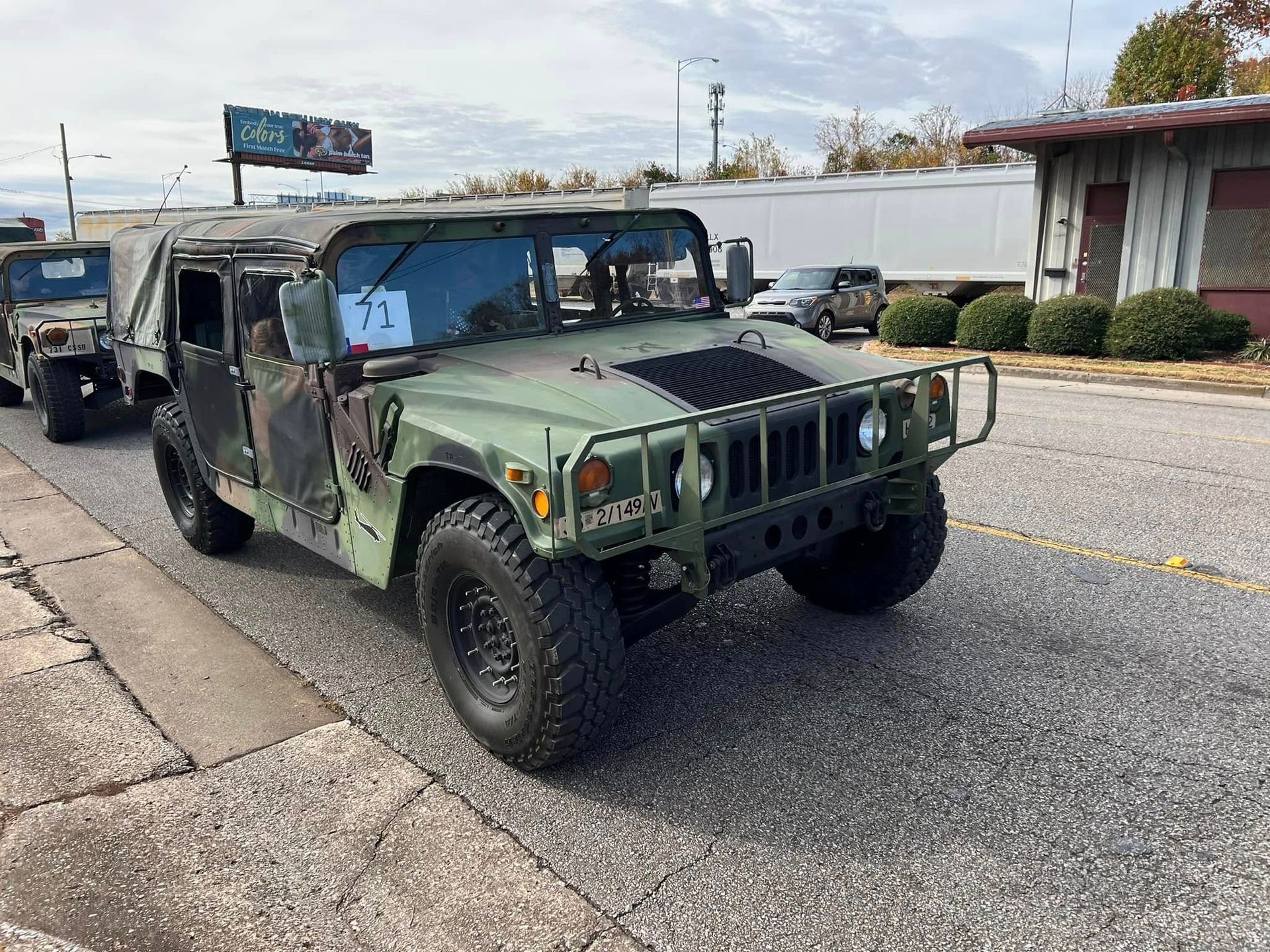 Camouflaged military Humvee parked on a street outside buildings