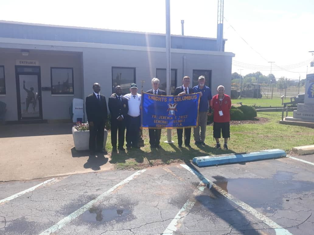 Group of people standing outside a building holding a blue banner during a community event