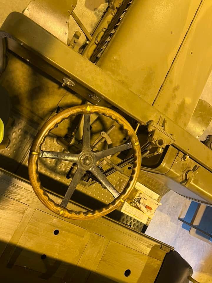 Yellow industrial machine wheel with spokes and a toothed rim inside a factory setting