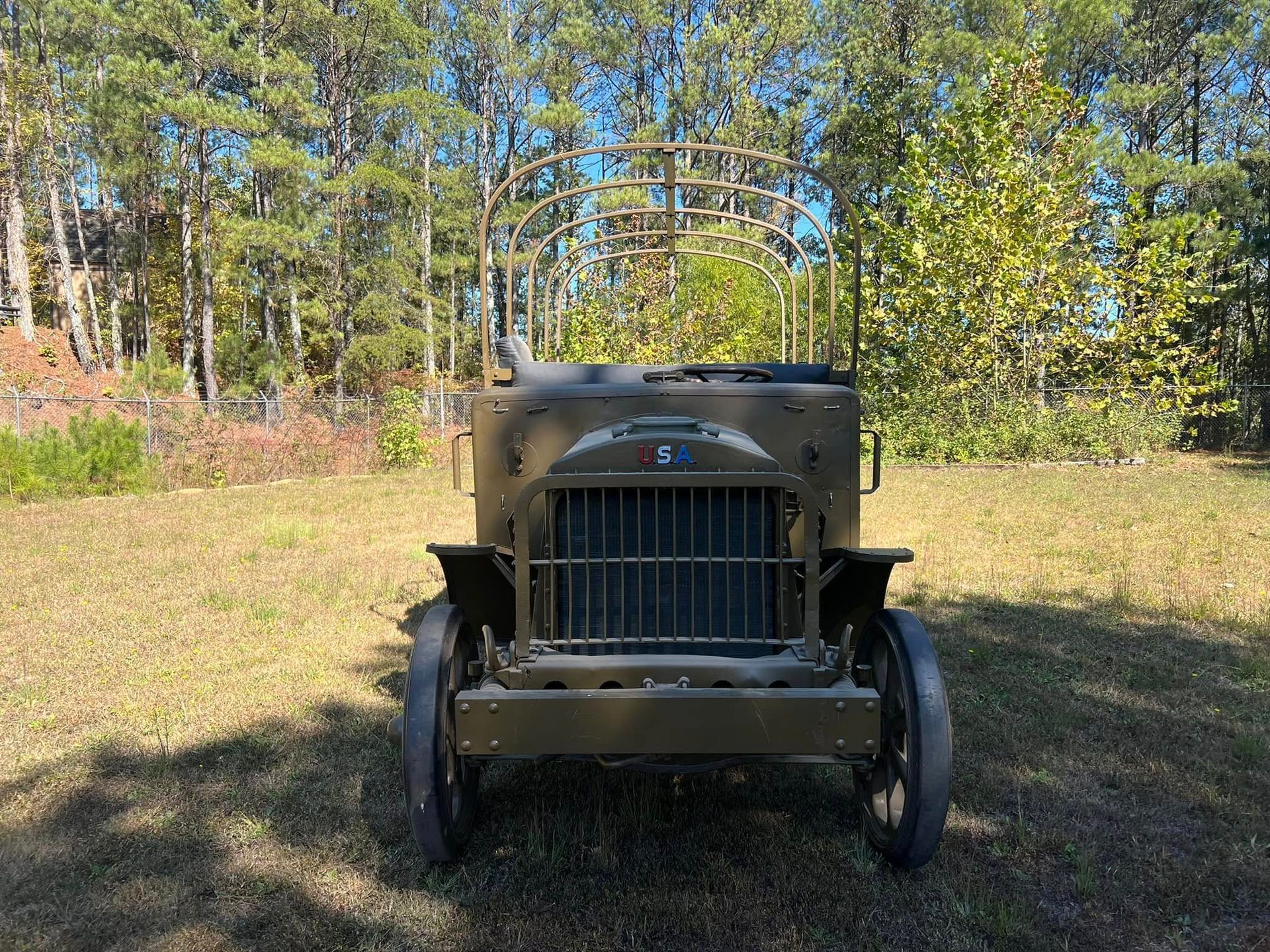 Vintage military truck parked on a grassy field with trees in the background.