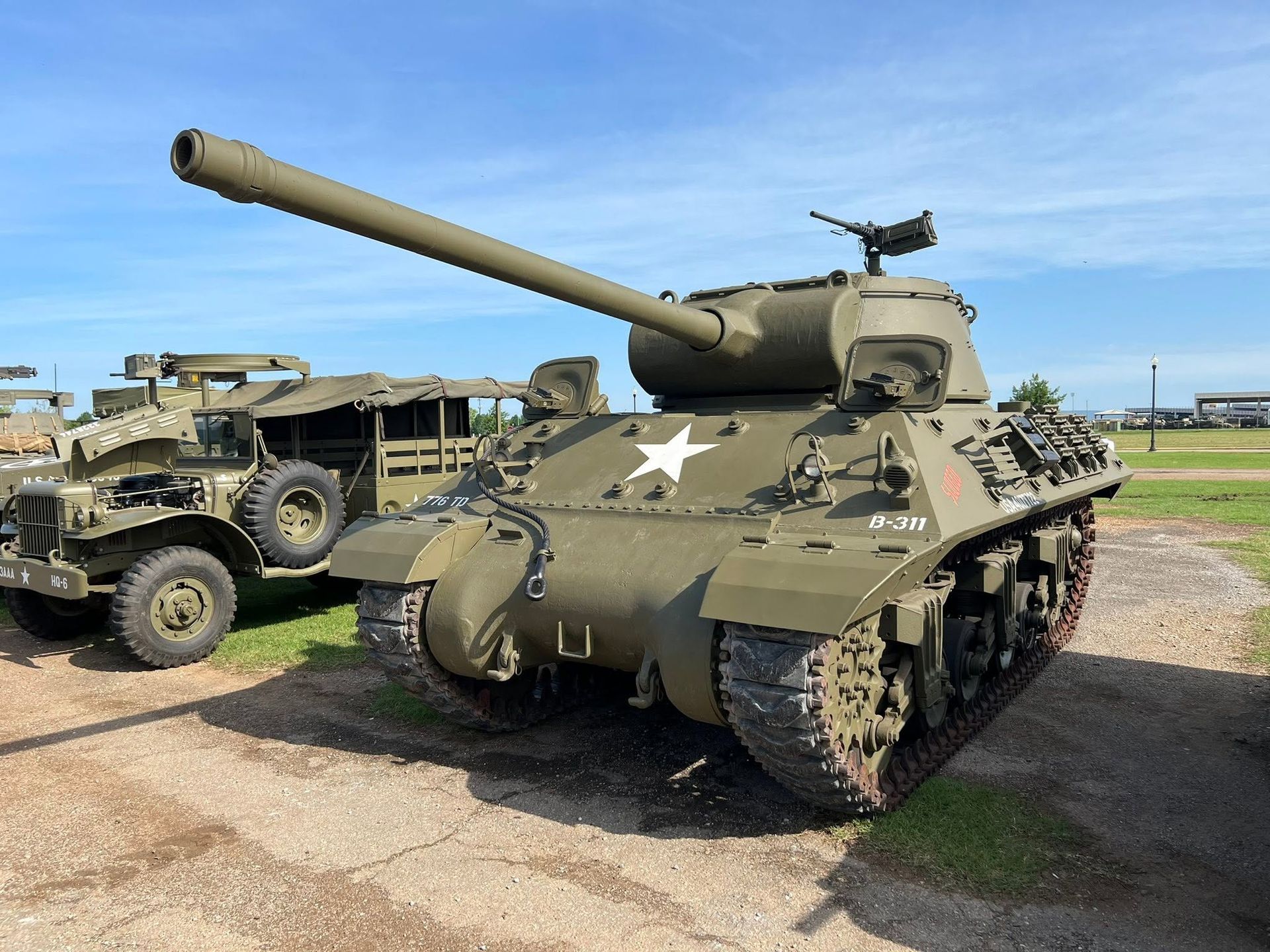 World War II tank on display outdoors beside a military vehicle on a grassy field