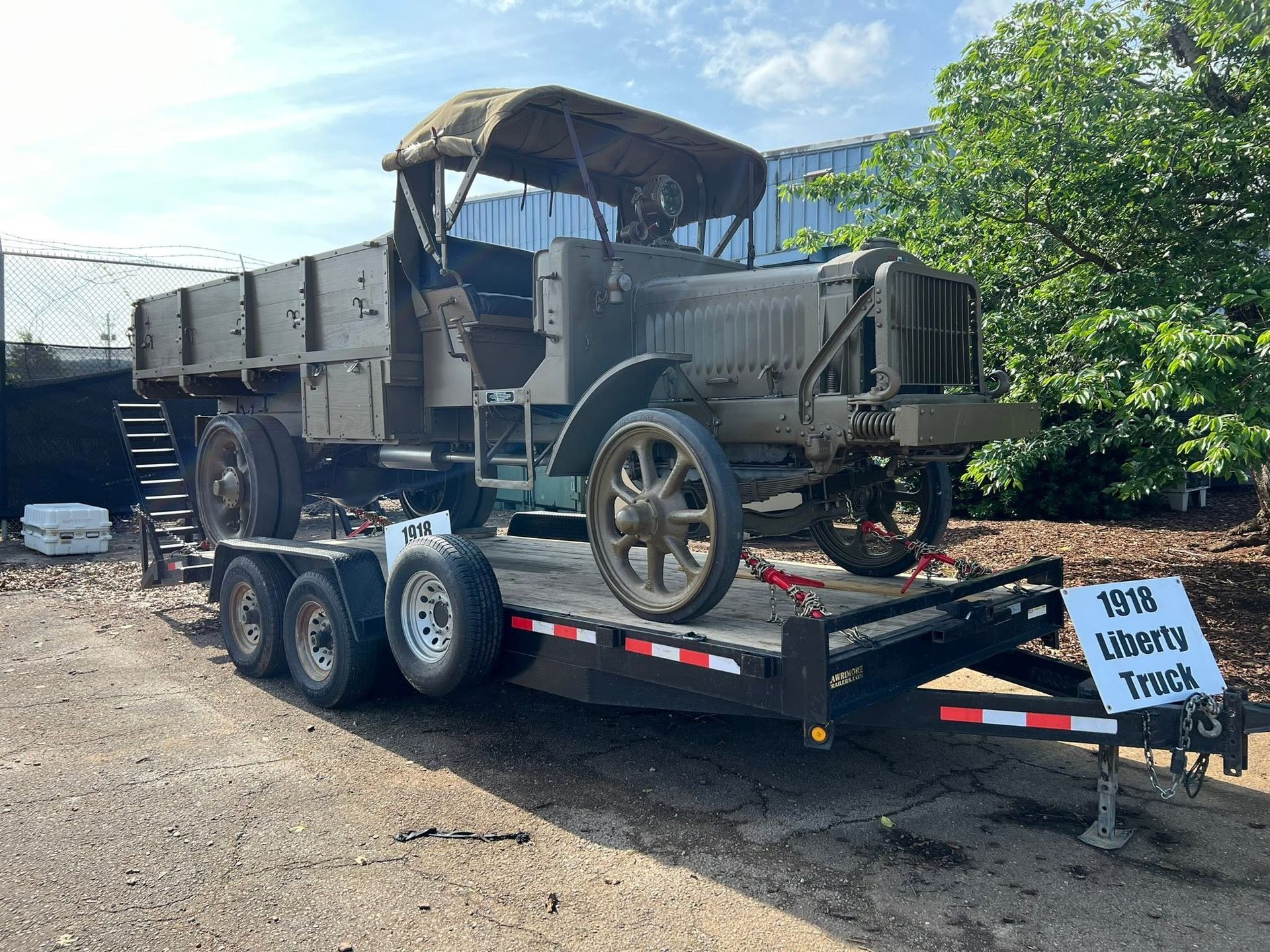 Vintage military truck displayed on a trailer outdoors at a salvage yard