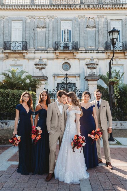 A bride and groom are posing for a picture with their bridesmaids in front of a building.
