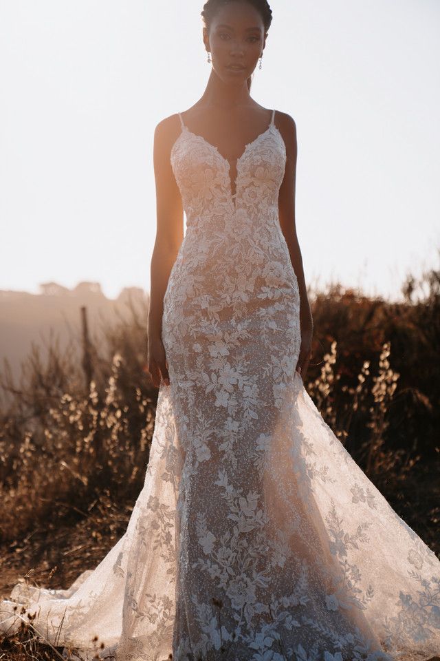 A woman in a wedding dress is standing in the grass.