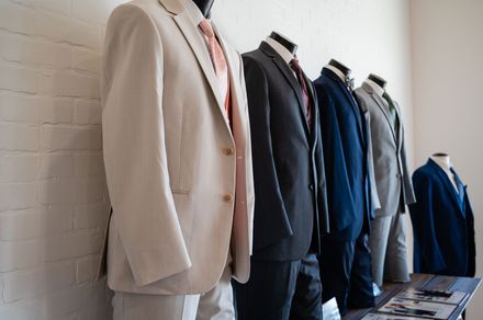 A row of suits are lined up on mannequins in a room.