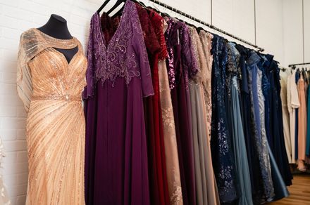 A row of dresses are hanging on a rack in a store.