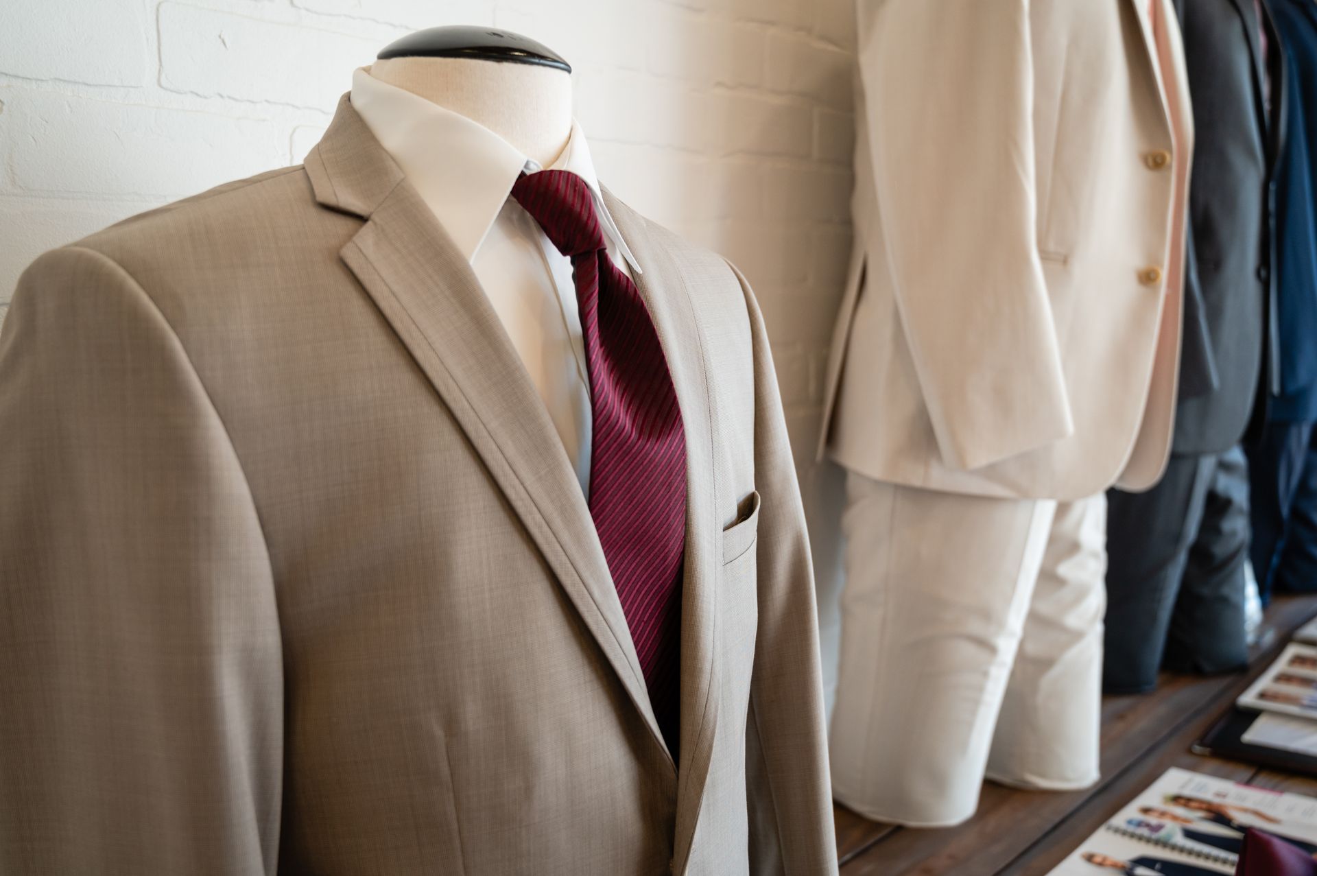 A tan suit with a red tie is on a mannequin.