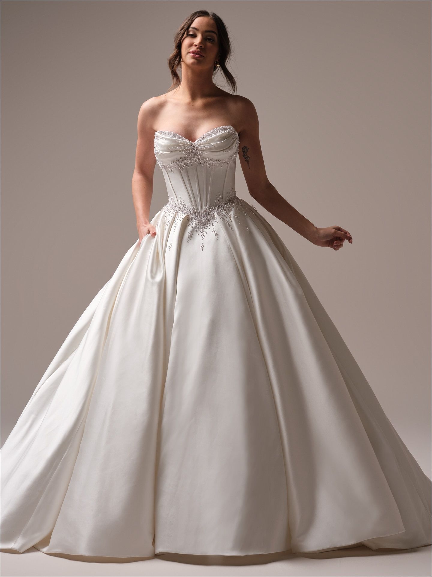 Woman in a strapless white ballgown with jeweled bodice, hands in pockets.
