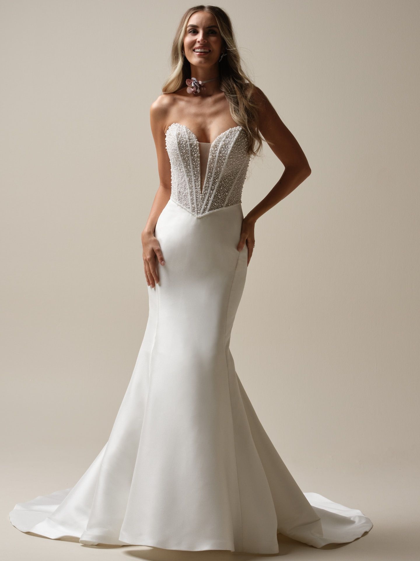 Woman in white mermaid gown with beaded bodice, smiling.