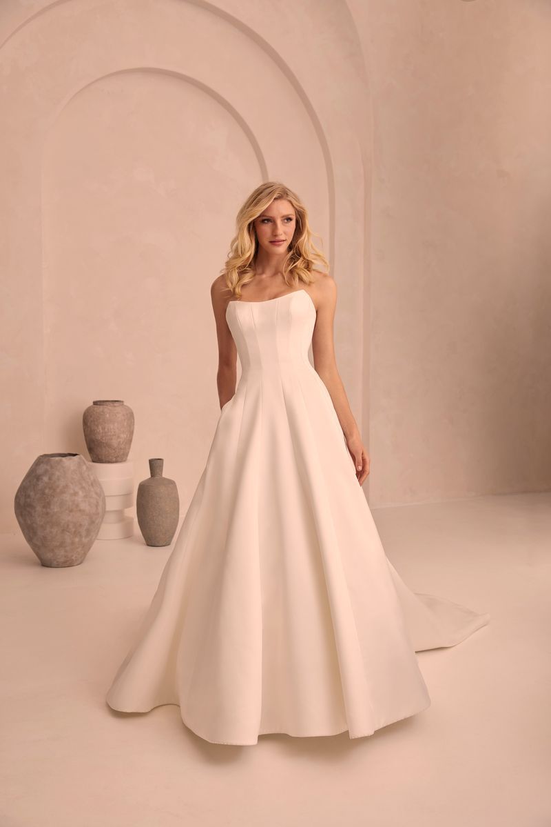 A woman in a white wedding dress is standing in front of vases.
