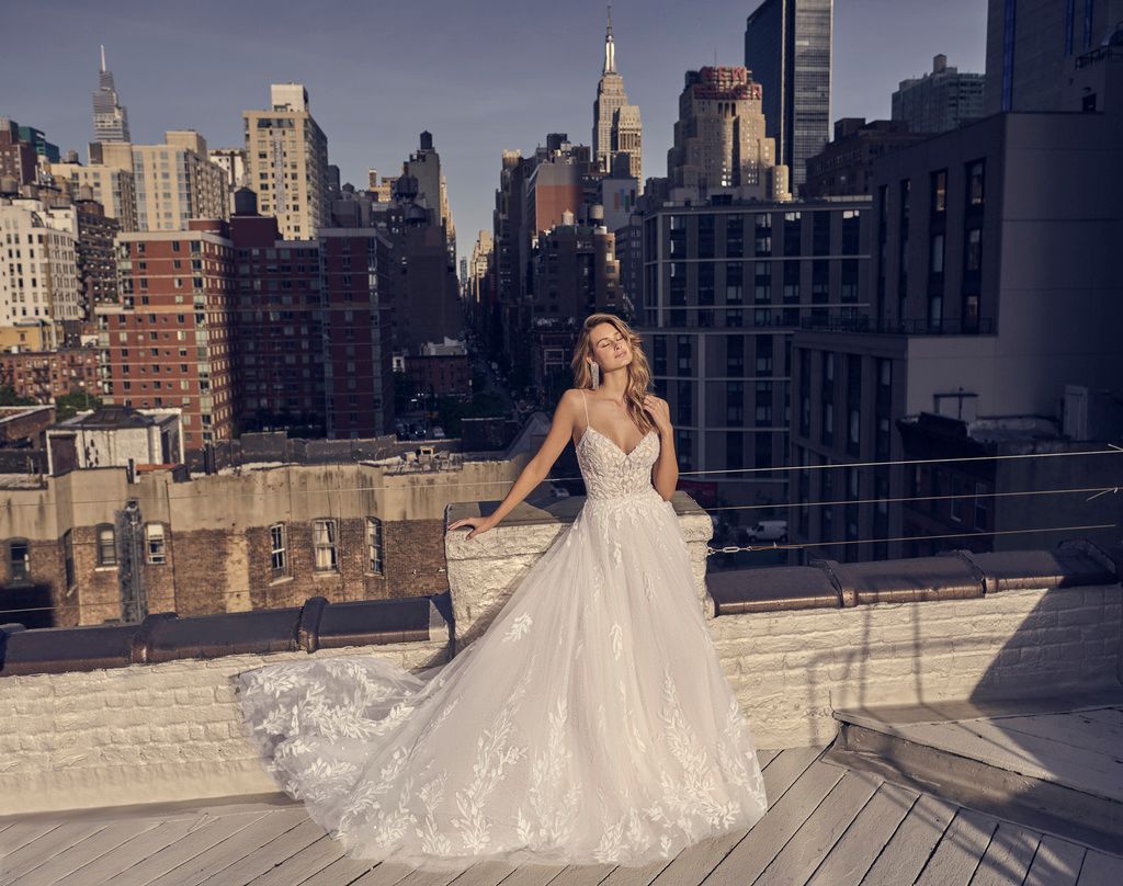 A woman in a wedding dress is standing on a balcony overlooking a city.