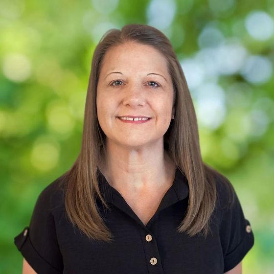 A woman in a black shirt is smiling for the camera.