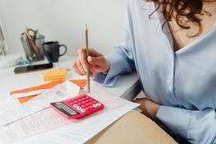 A woman is sitting at a desk using a calculator and a pencil.