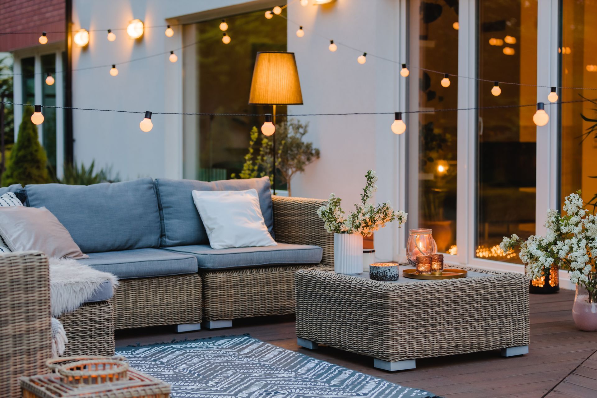 Modern outdoor patio with wicker furniture and string outdoor lighting.