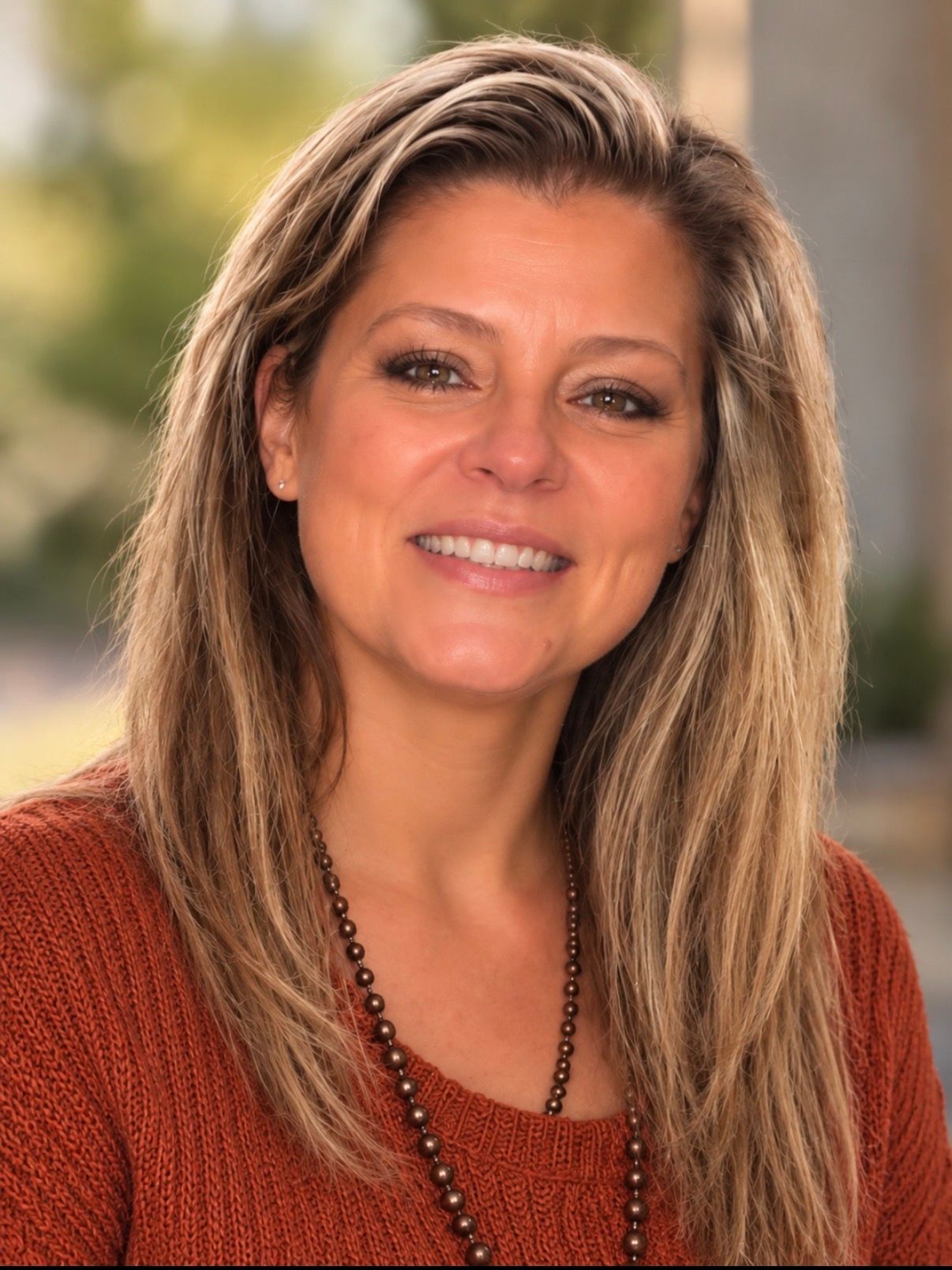 A woman with long blonde hair is smiling and wearing a black shirt.