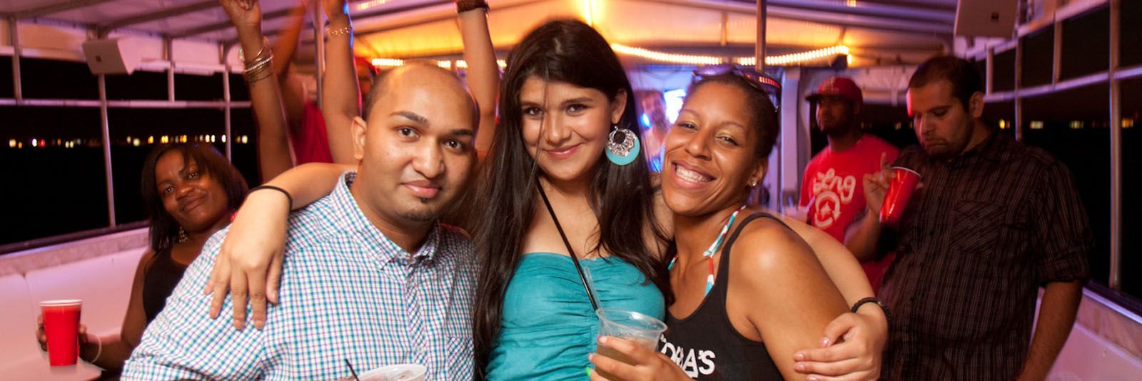 Group of people smiling and posing for a photo at a nighttime event on a boat.