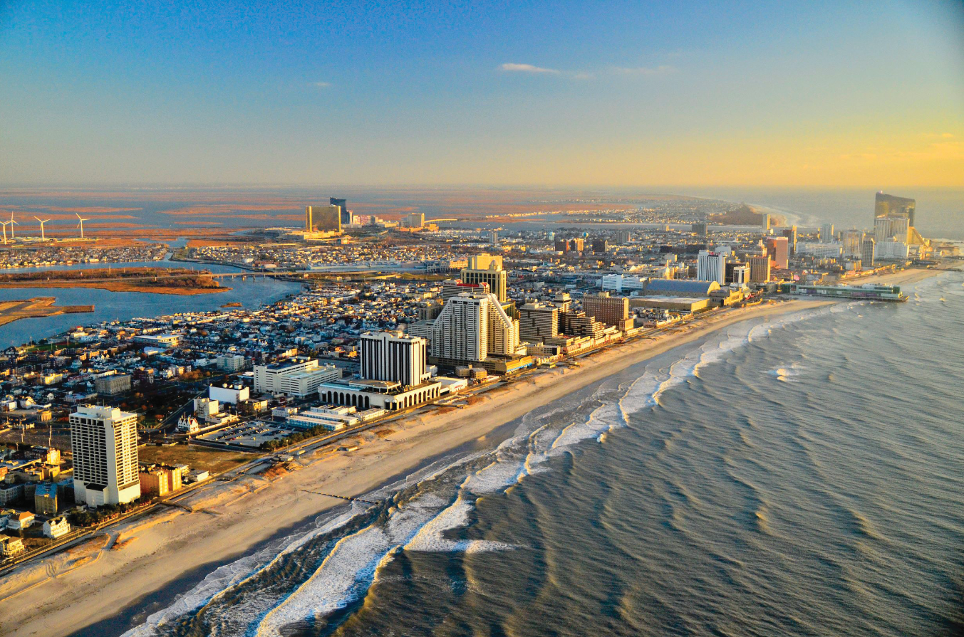 Aerial view of Atlantic City, NJ: city skyline along beach, ocean waves, and blue sky.