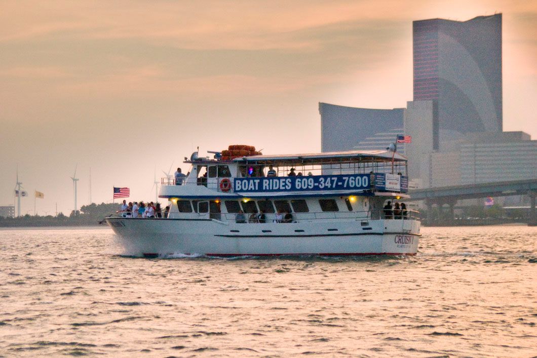 Boat cruising on water, with a city skyline backdrop.