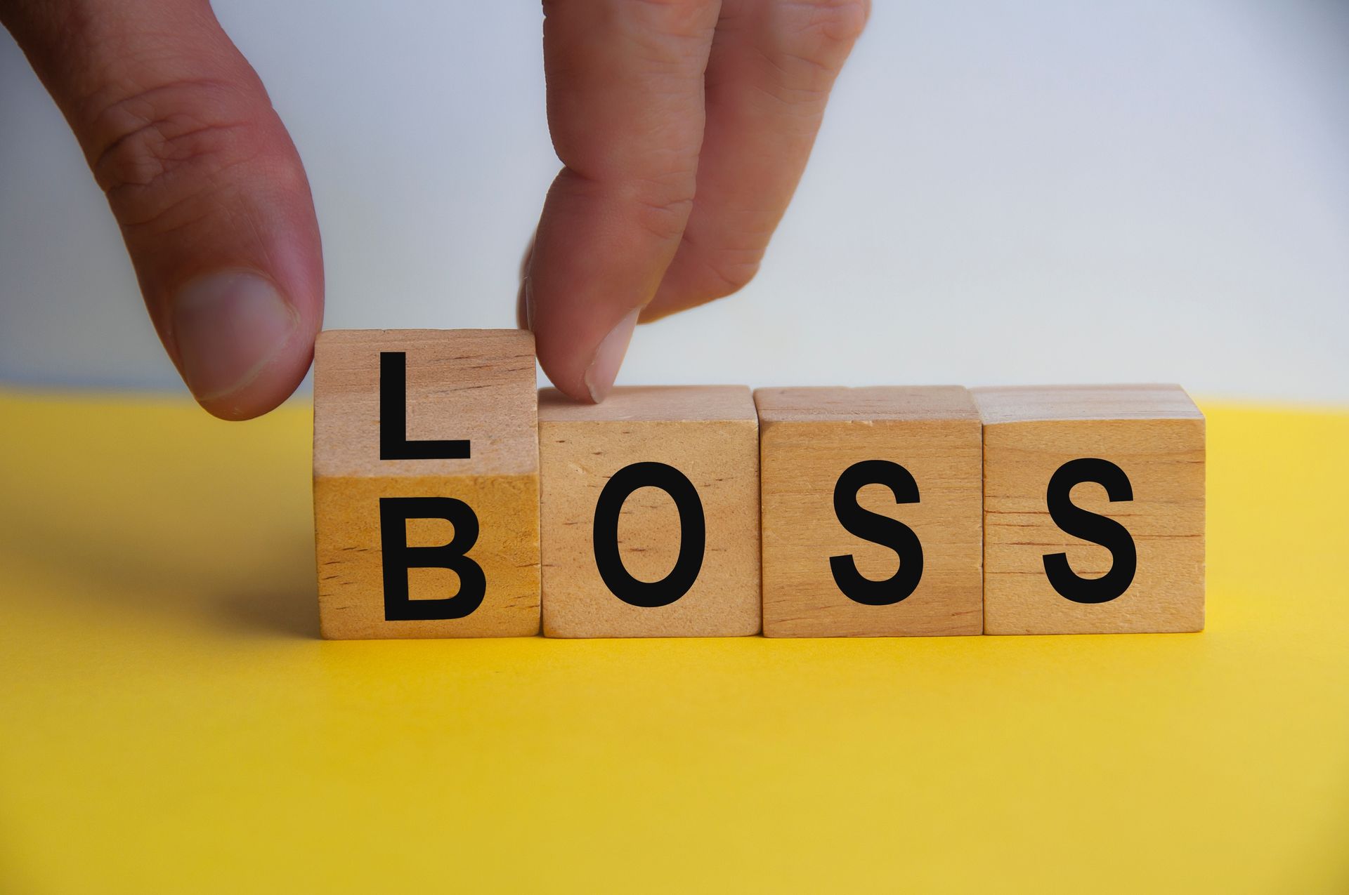 Hand turning wooden cube to LOSS BOSS. Copy space. Poor business management concept.