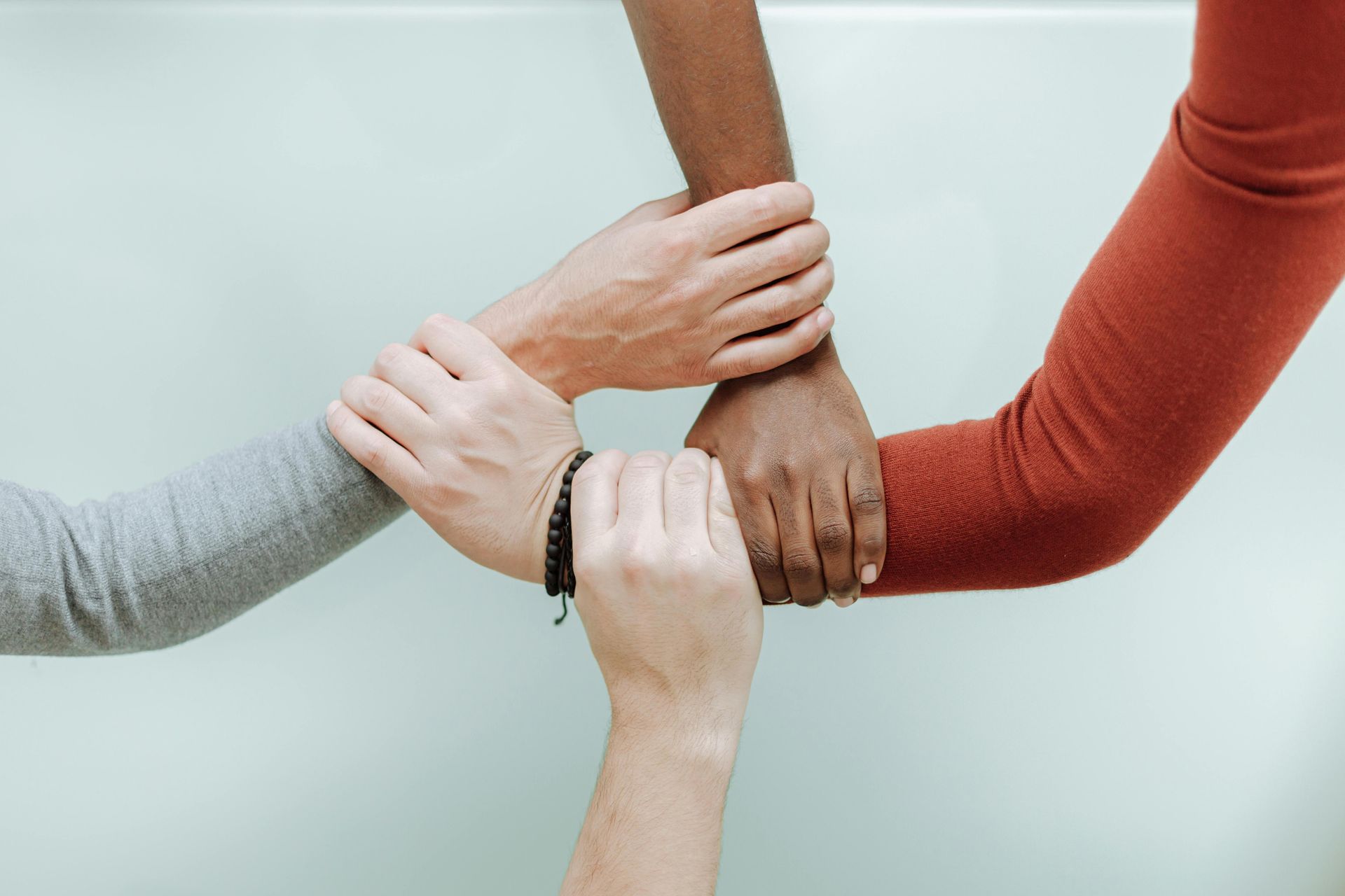 Hands of diverse people clasped together in a triangle, symbolizing unity and collaboration.