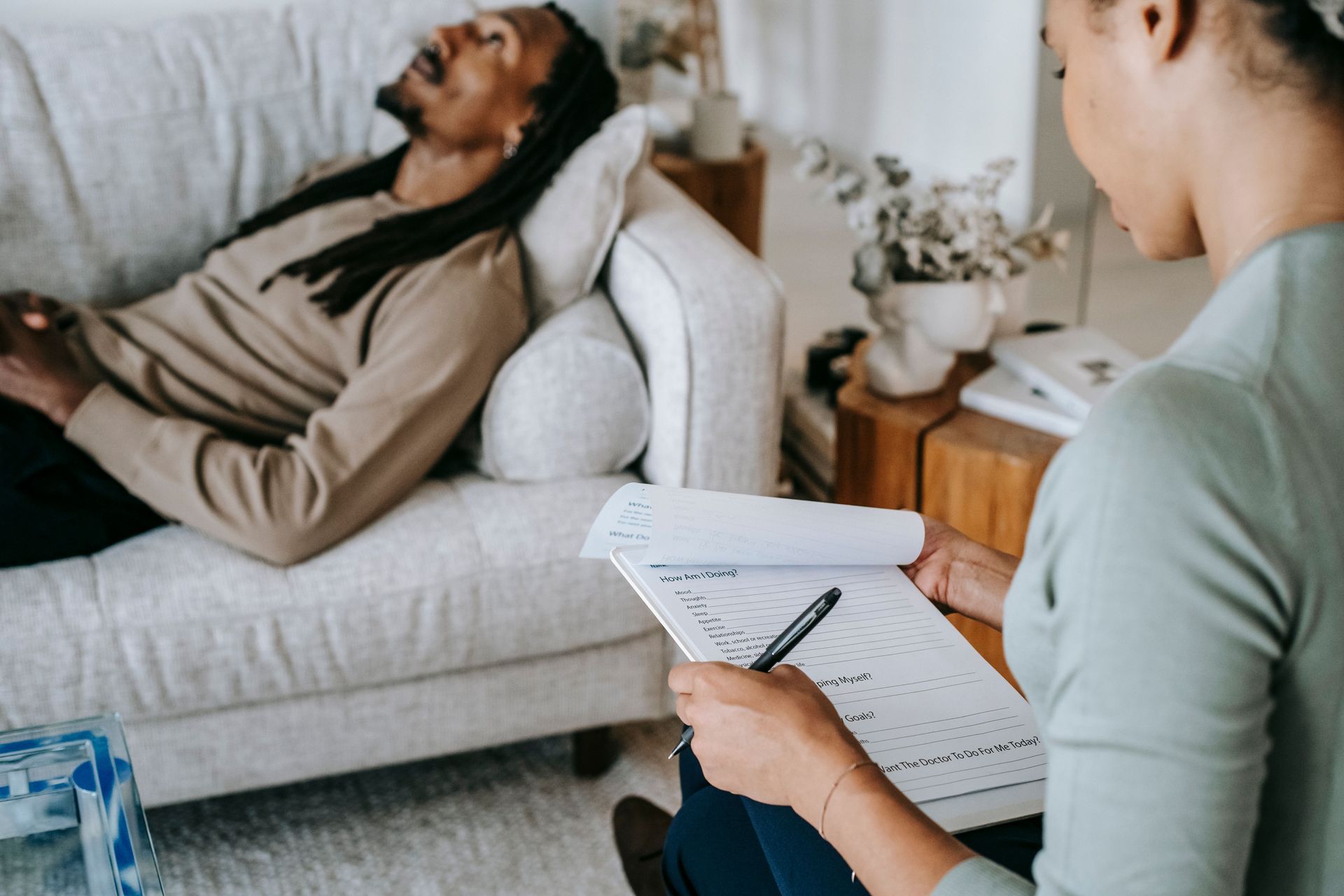 Counseling session with a client on a sofa and a therapist taking notes nearby