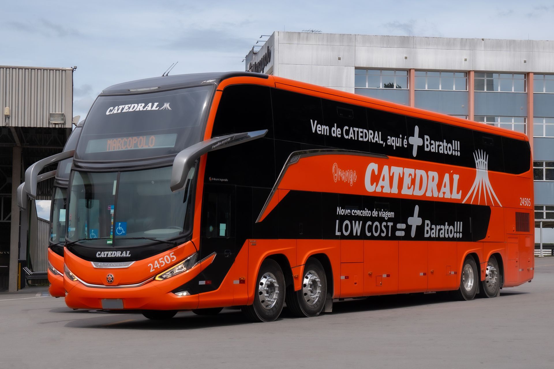 Ônibus Catedral de dois andares laranja e preto estacionado em frente a um prédio.