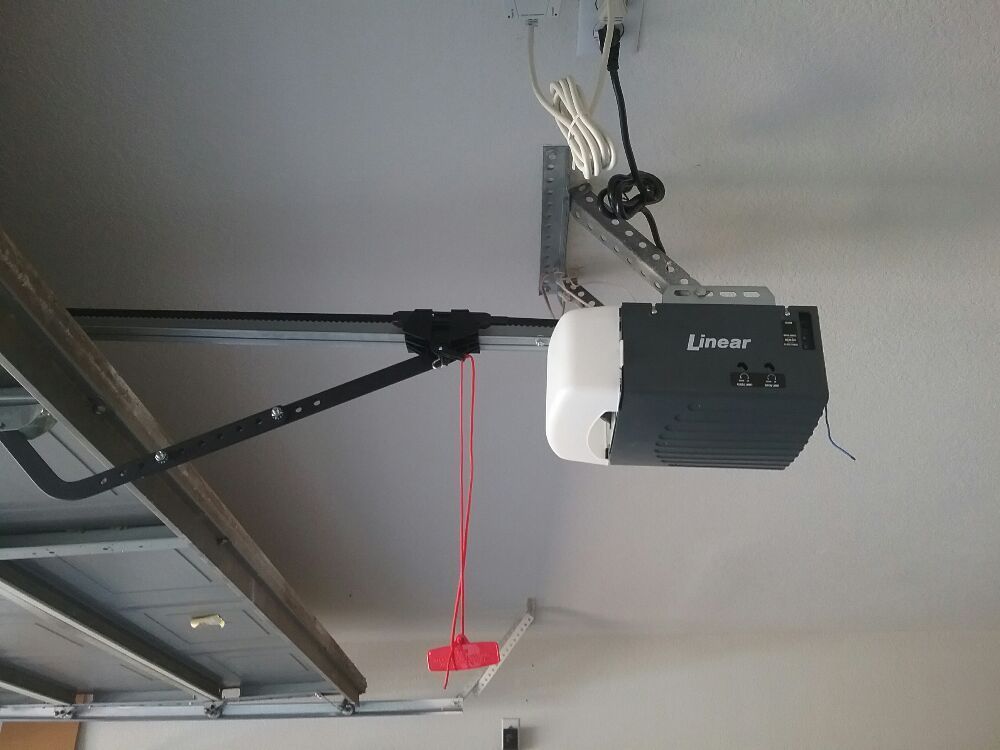 Garage ceiling with a black garage door opener, red pull cord, and overhead track.