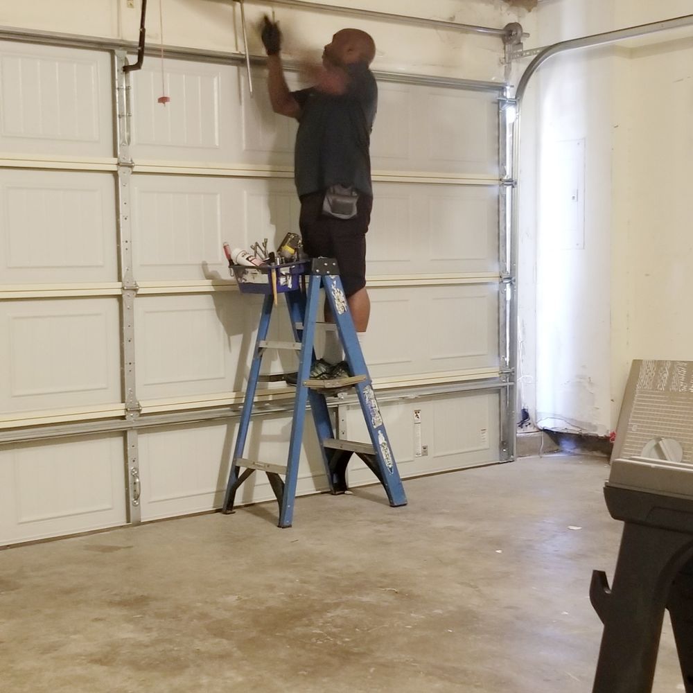 Person on a blue step ladder working on the garage door opener in a garage.