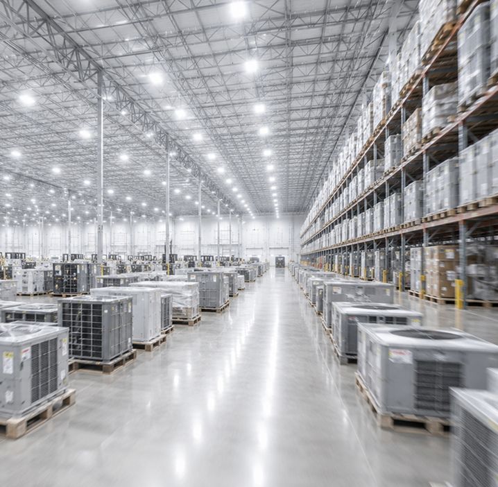 Bright, spacious warehouse with rows of stacked pallets and shelving under high ceiling lights