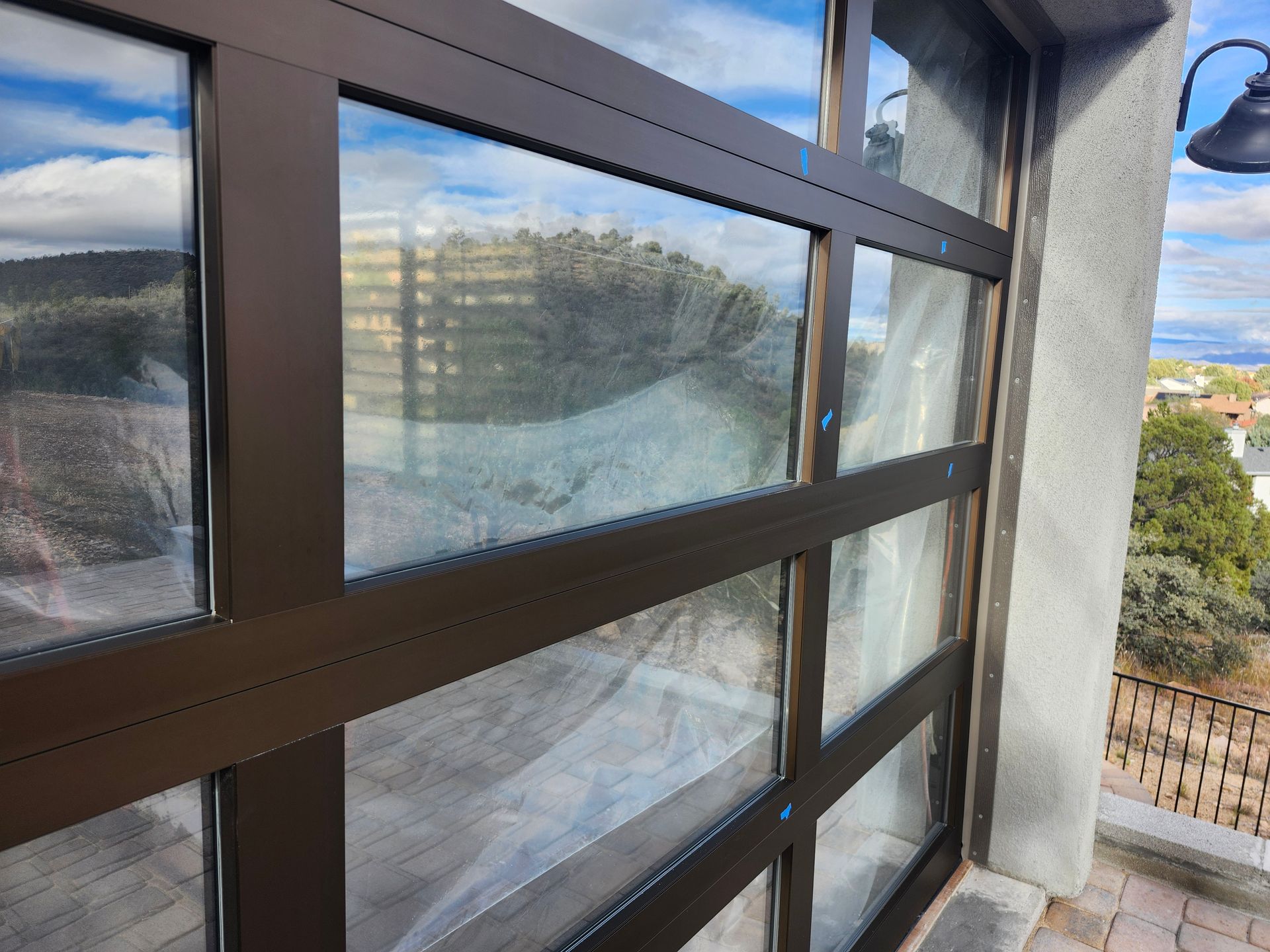 Brown-framed glass door, exterior view, partially open, with landscape visible through the panels.