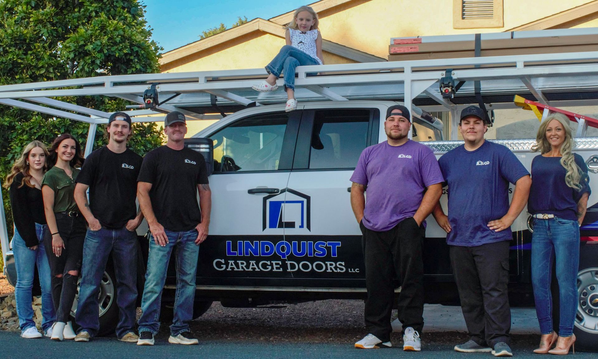 Team of Lindquist Garage Doors posing with truck, child on roof.