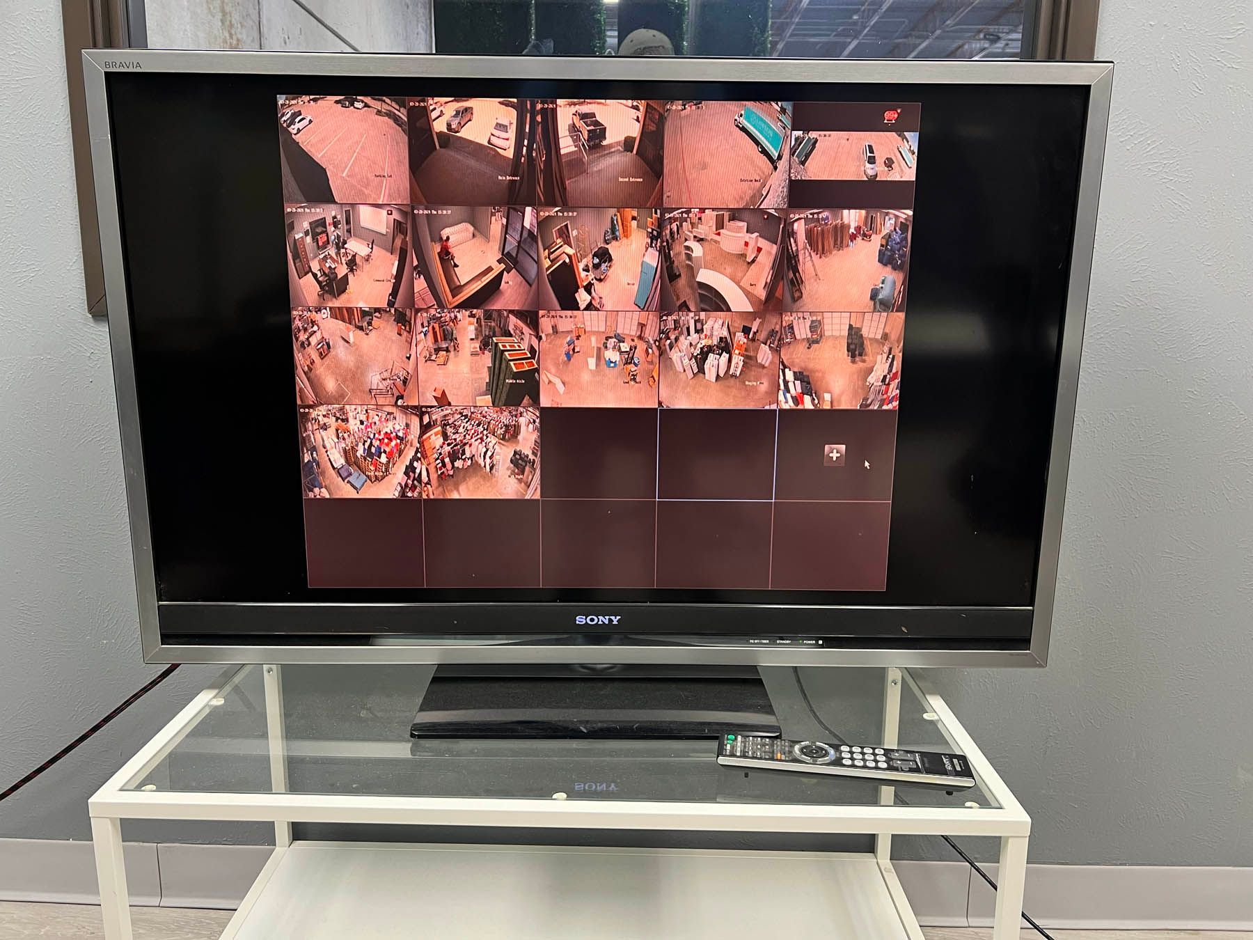 TV displaying a grid of images, a remote, and a media player on a glass table.