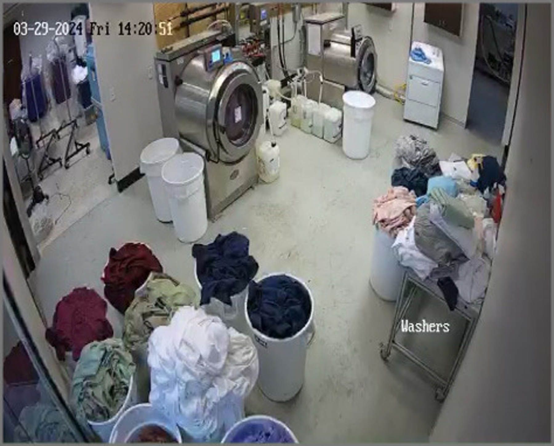 Laundry room with washing machines, bins of sorted clothes, and cleaning supplies.