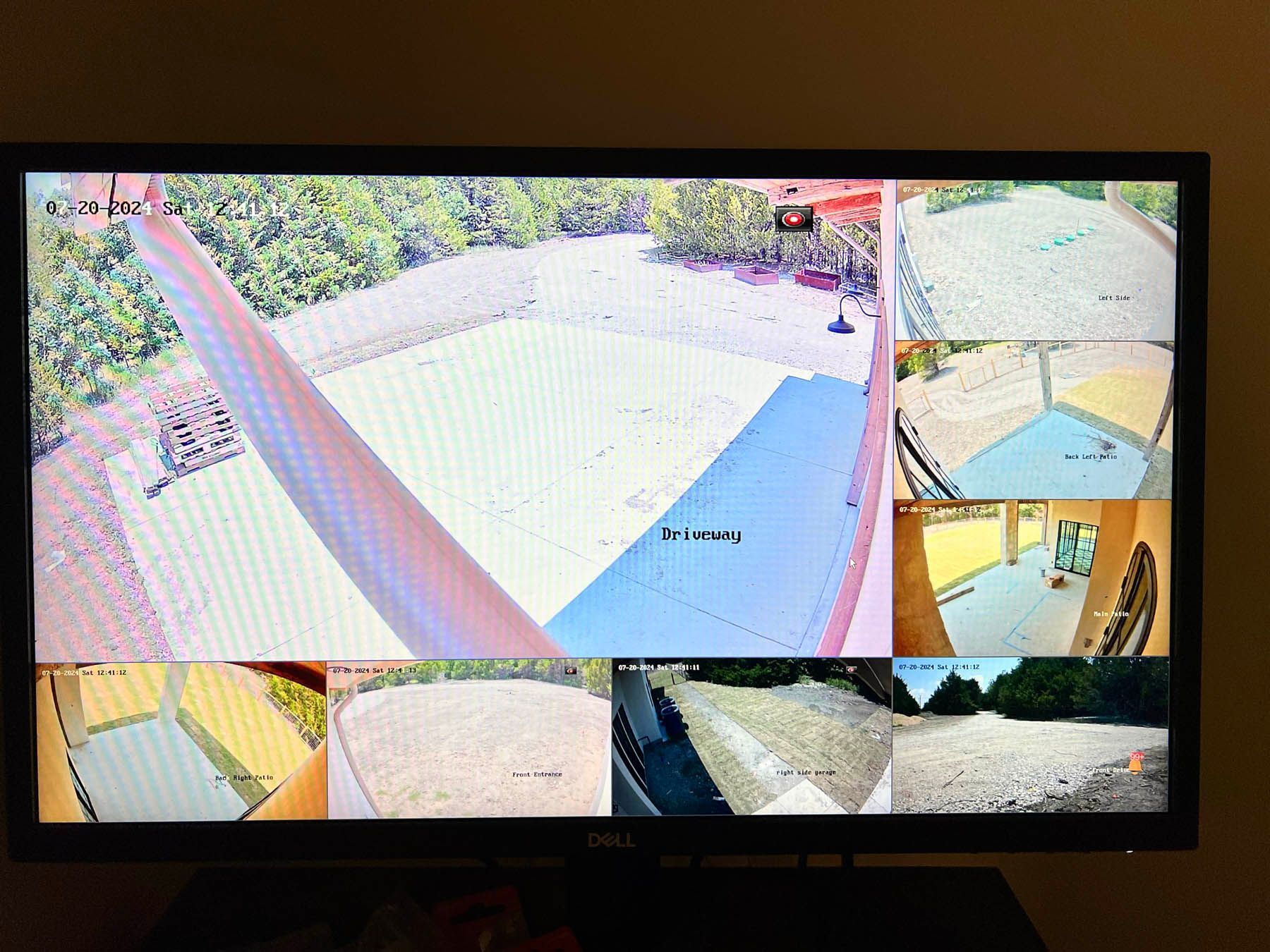 Security camera view of an airplane wing and other outdoor areas, displayed on a TV screen.