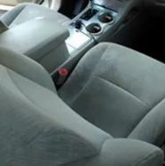 Gray car seats and center console with cup holders in a vehicle interior.