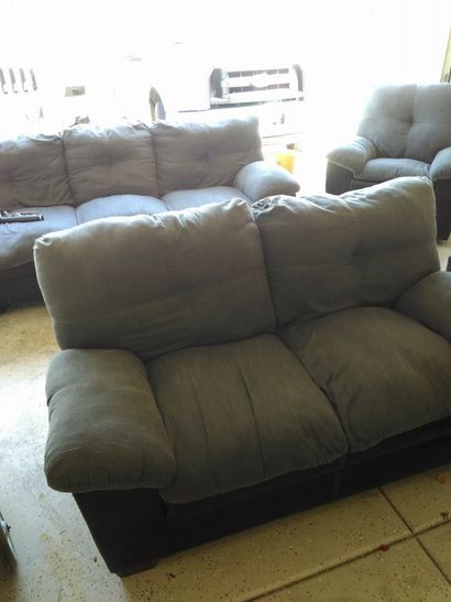 Two brown sofas in a bright living room with tiled floor and a recliner chair in the back