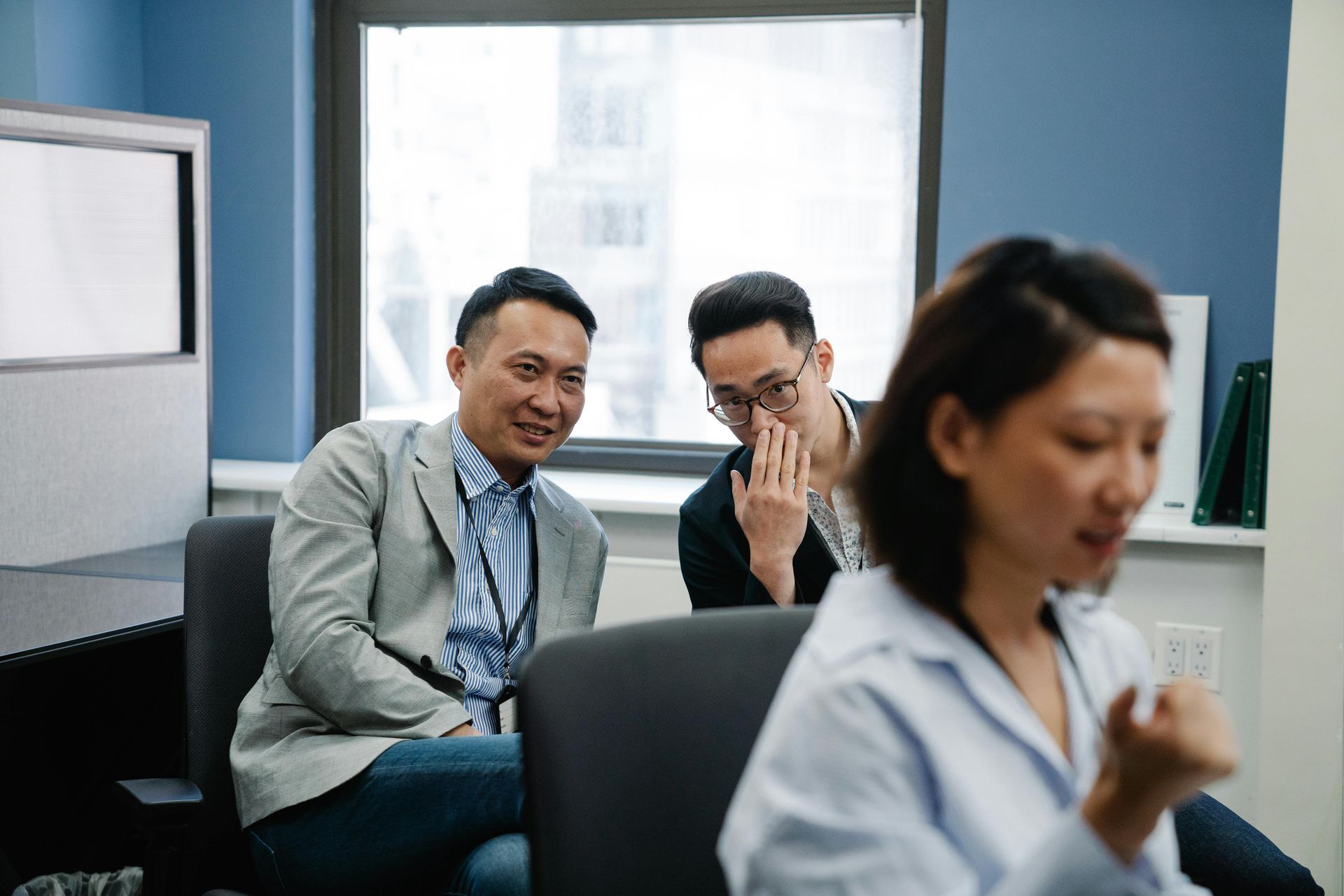 Office workers engaging in workplace gossip and unprofessional behavior while colleague works nearby