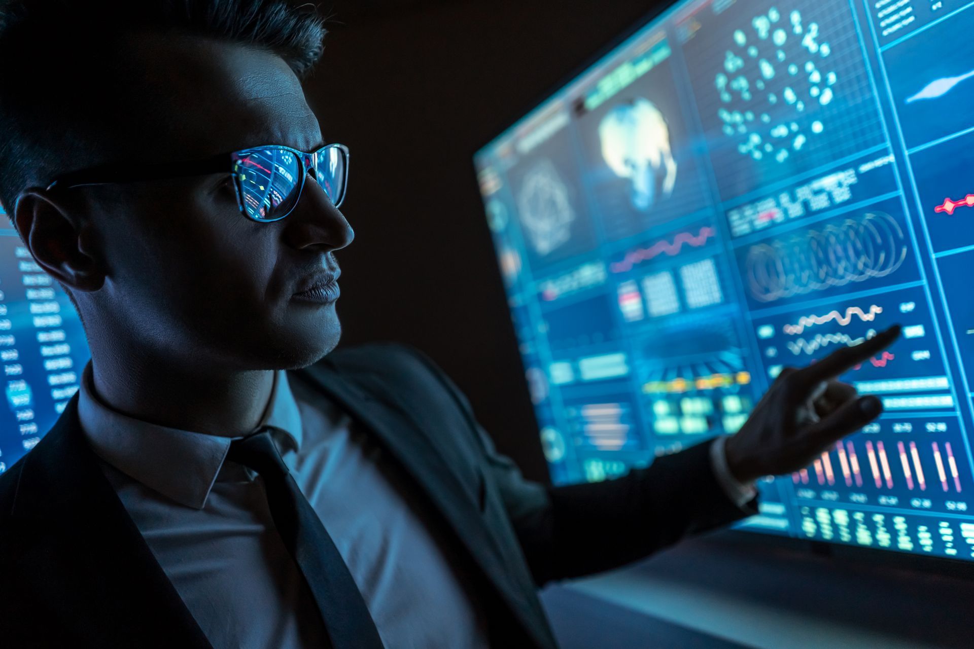 A man in a suit and tie is pointing at a computer screen.
