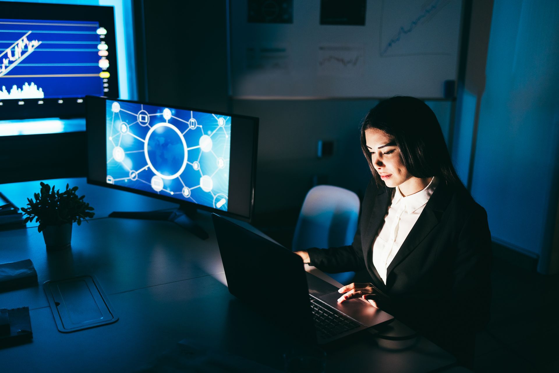 A woman is sitting at a desk in front of a laptop computer.