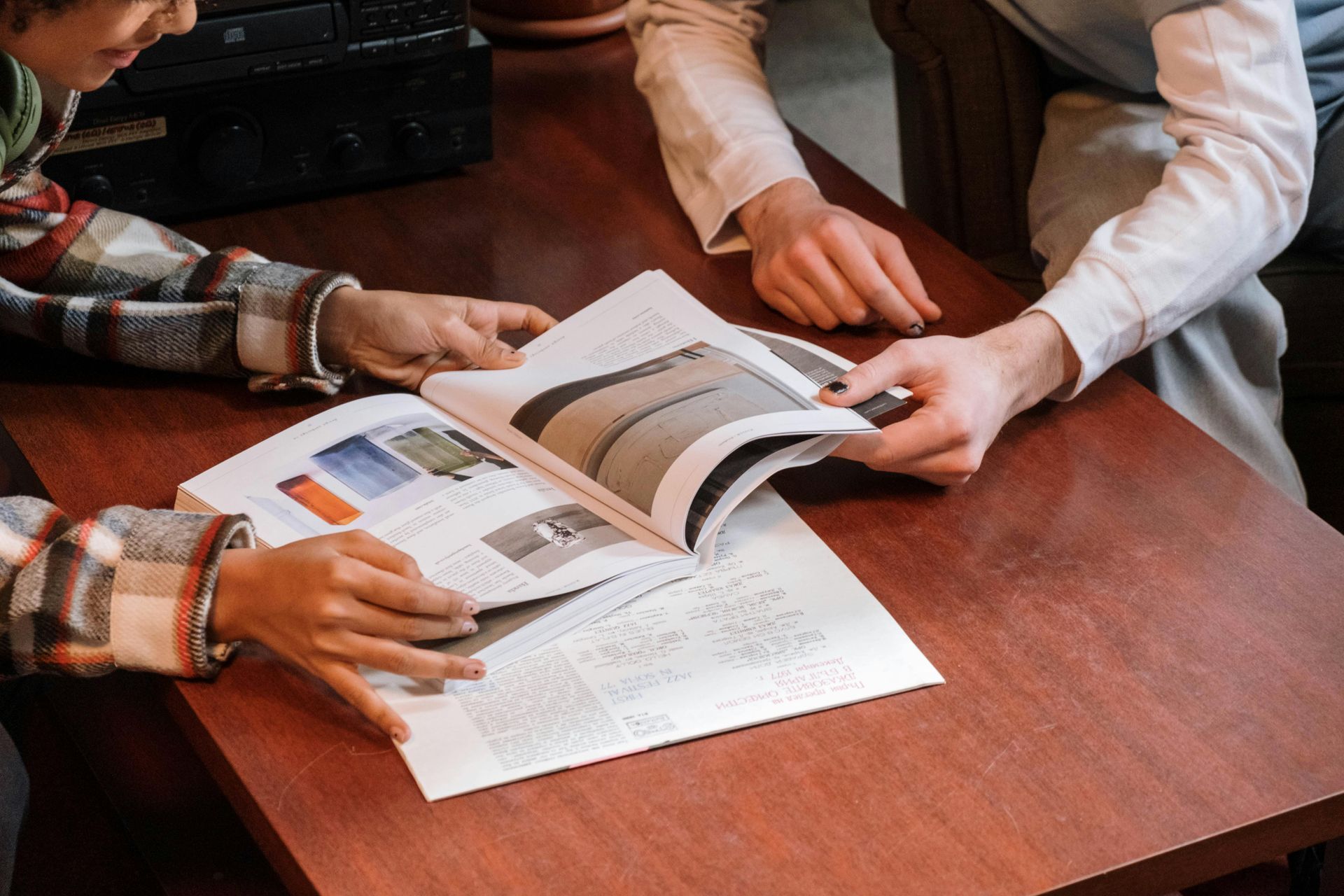 Two people are sitting at a table looking at a magazine.