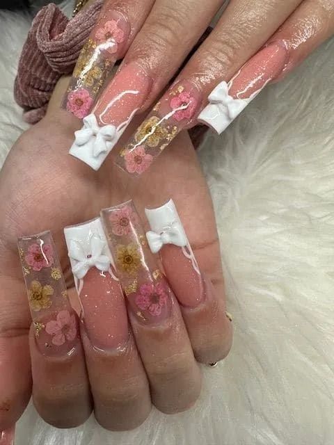 A close up of a person 's nails with flowers and bows.