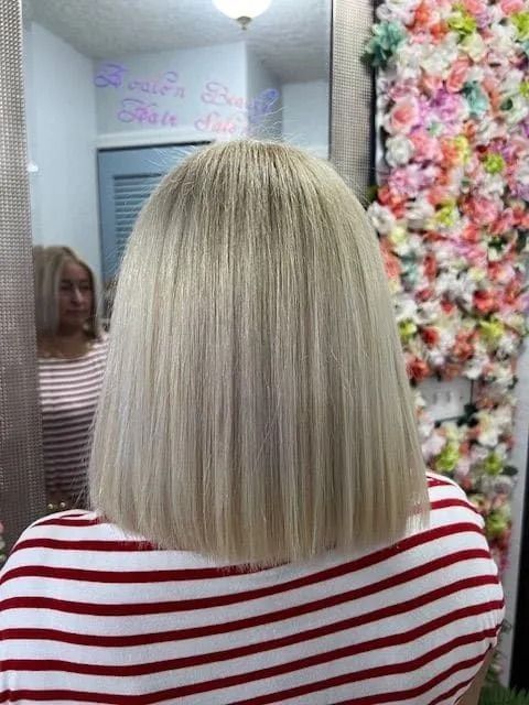 A woman with blonde hair is sitting in front of a mirror.
